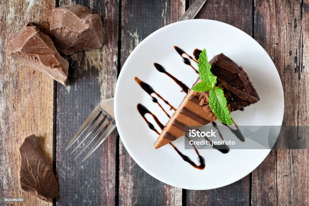 Chocolate cheesecake above view over rustic wood Slice of chocolate cheesecake on plate, above view over a rustic wood background Dessert - Sweet Food Stock Photo