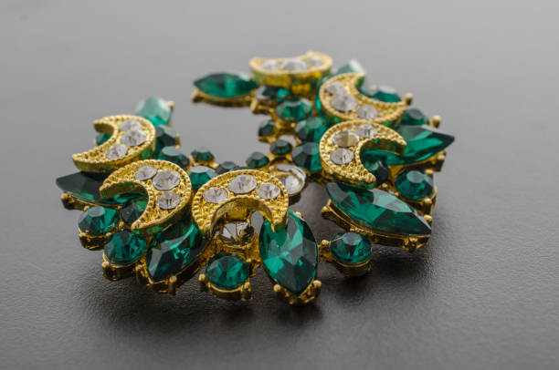 istock golden brooch with emeralds and diamonds isolated on black 865590106
