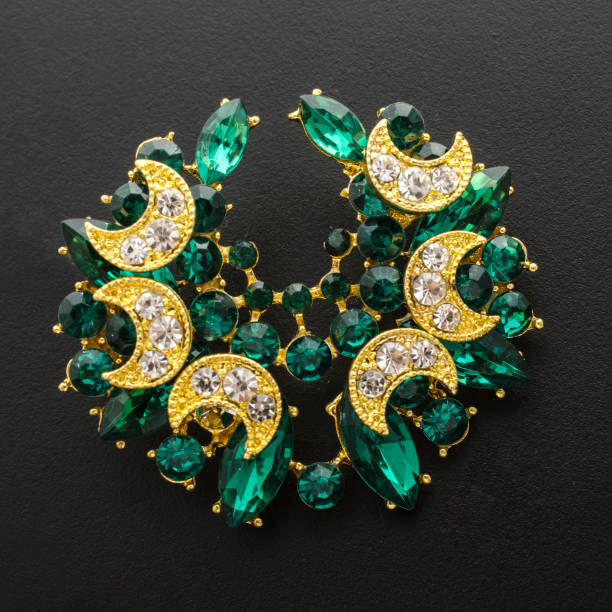 istock golden brooch with emeralds and diamonds isolated on black 865590128