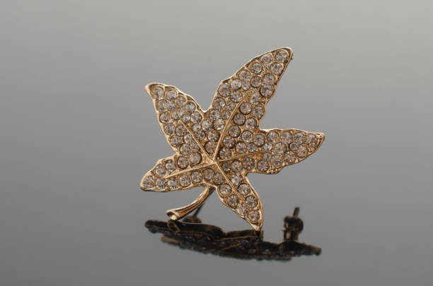 istock gold brooch maple leaf with diamonds isolated on black 865590144