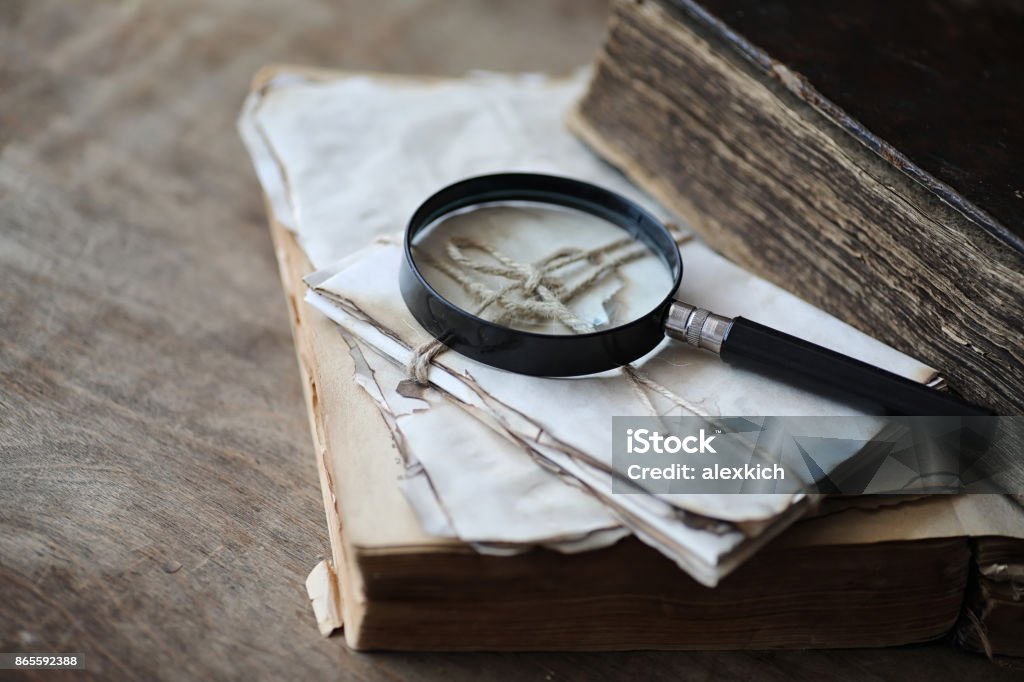 Old books on a wooden table and magnifier Old books on a wooden table and glass magnifier Detective Stock Photo