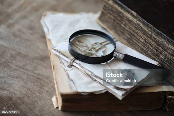 Old Books On A Wooden Table And Magnifier Stock Photo - Download Image Now - Detective, Magnifying Glass, Research