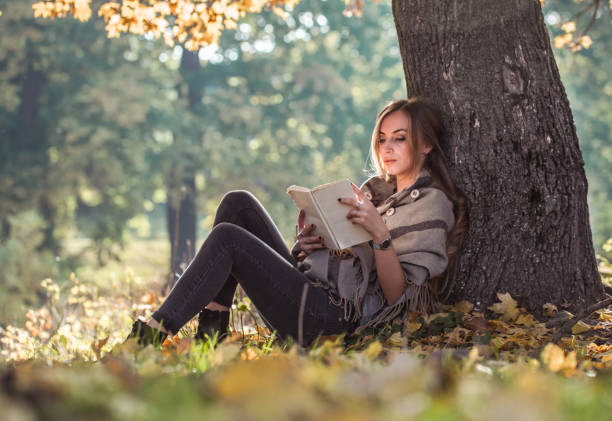 istock beautiful girl reading a book in autumn forest 865596186