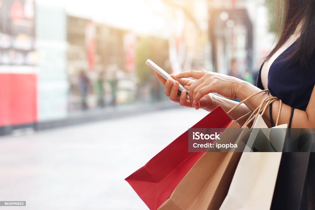 Frau mit Smartphone und halten Einkaufstasche stehend auf der Mall-Hintergrund - Lizenzfrei Einzelhandel - Konsum Stock-Foto
