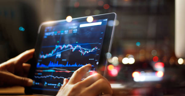 istock Businessman checking stock market data on tablet on night background 865596966