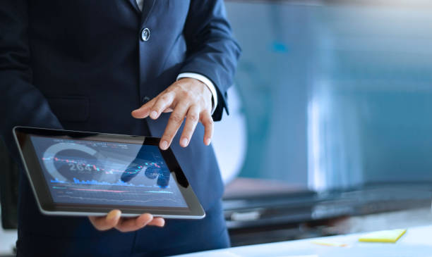 Analyzing data, Businessman working and checking market data in office, hand pointing on the data presented in the chart on tablet