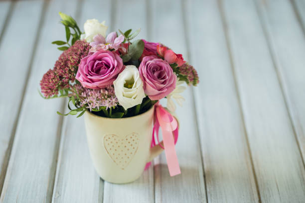 istock Beautiful flowers in cup on wooden background 865601340