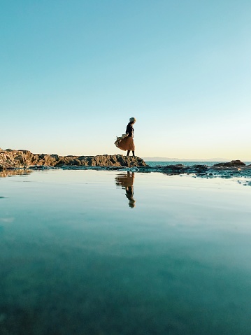 Woman standing on rock beside sea
