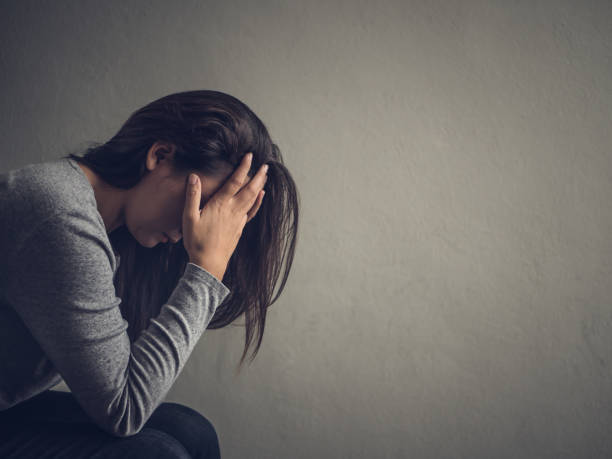 depressieve vrouw zitten op een stoel in de donkere kamer thuis. lonly, verdrietig, emotie concept. - medische aandoening fotos stockfoto's en -beelden