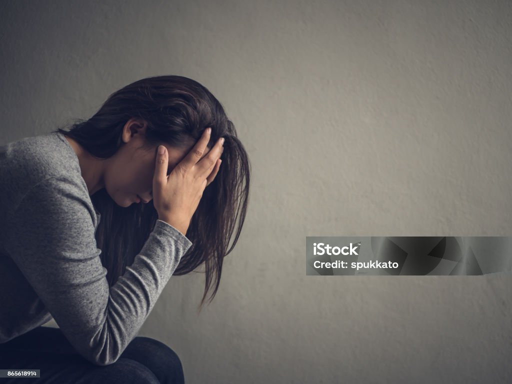Depressed woman sitting on a chair in dark room at home. Lonly , sad, emotion concept. Women Stock Photo