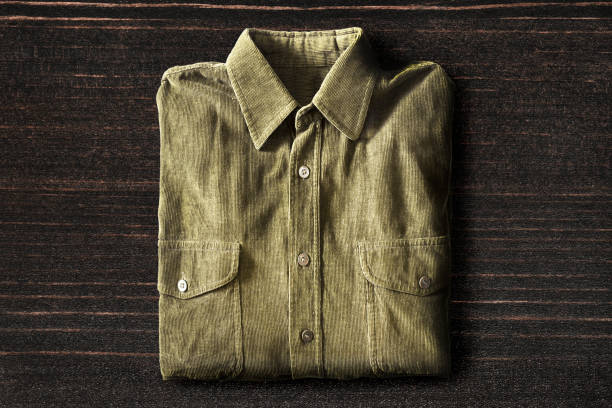 Shirt on wooden background Khaki velveteen shirt folded on dark wooden background corduroy jacket stock pictures, royalty-free photos & images