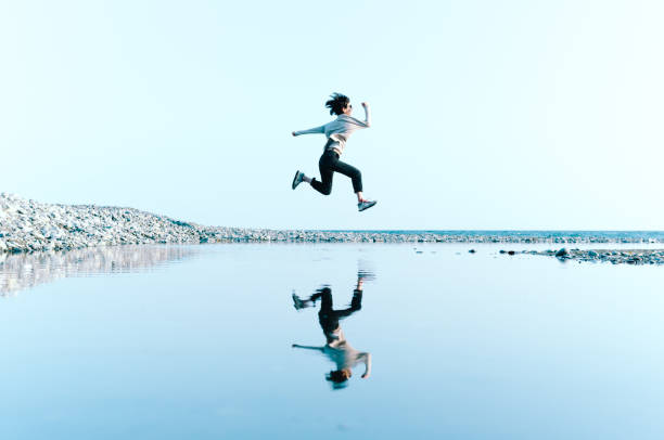 femme à sauter dans les airs au-dessus de l’eau disponibles dans une grande flaque - floating on water water women wet photos et images de collection