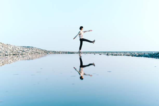 istock Woman Standing by Beach Reflected in Big Puddle 865620626