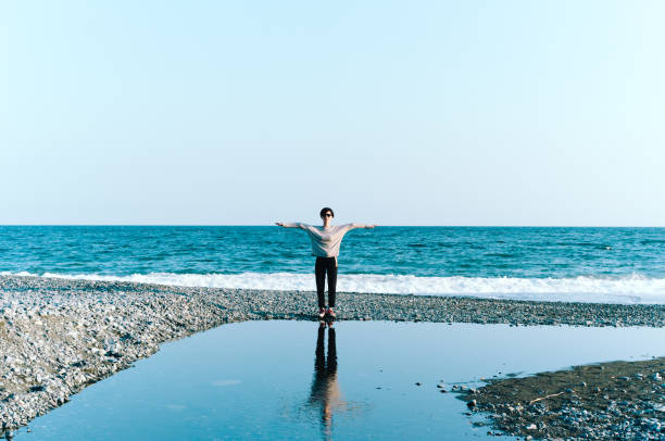 istock Woman Standing by Beach Reflected in Big Puddle 865620640