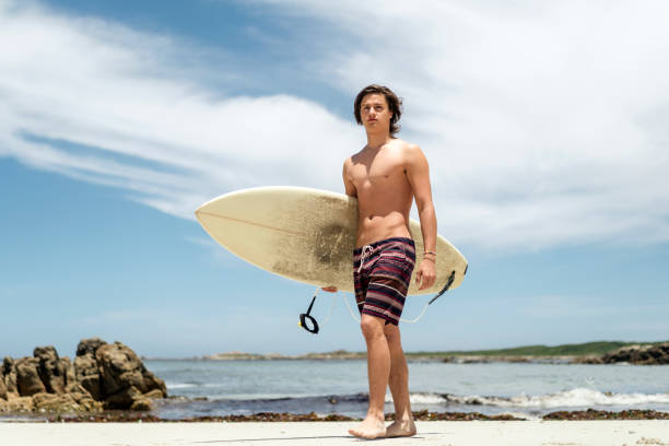 istock Shirtless man carrying surfboard at beach 865623556