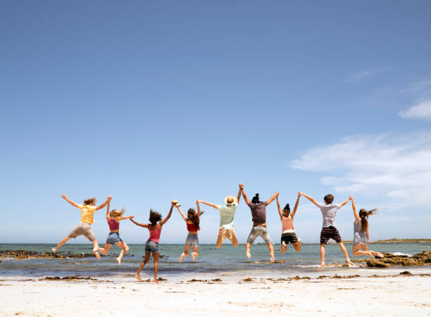 Friends holding hands and jumping at the beach