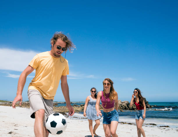 istock Young man playing soccer with women at beach 865631312