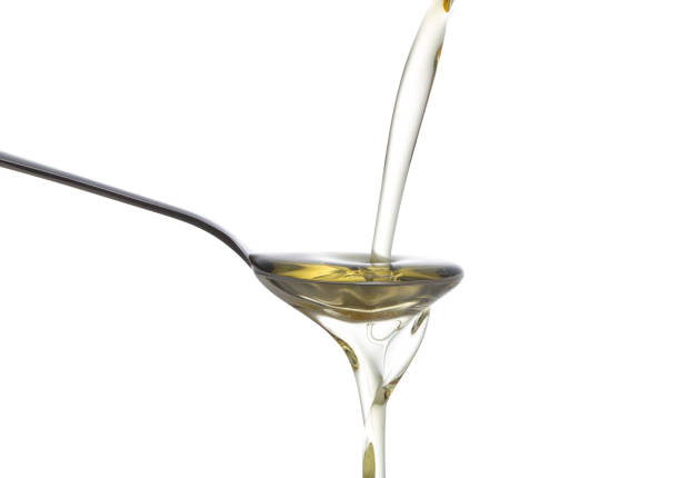 istock Olive oil poured from a bottle into a spoon isolated on white background 865631422