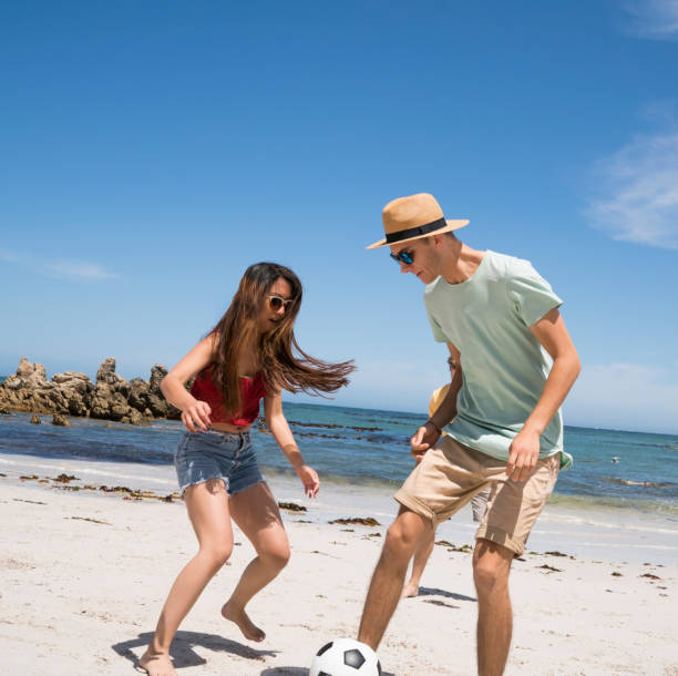 istock Young man and woman playing soccer at beach 865631472
