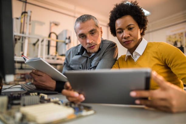 Two engineers working on digital tablet in tech laboratory. IT technicians surfing the net on touchpad working on new project in laboratory. technology office equipment laboratory stock pictures, royalty-free photos & images