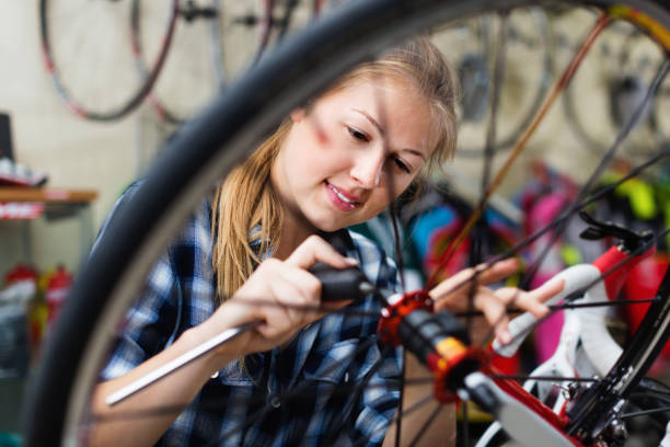 istock Female is fixing wheels of bicycle in workshop. 865638674