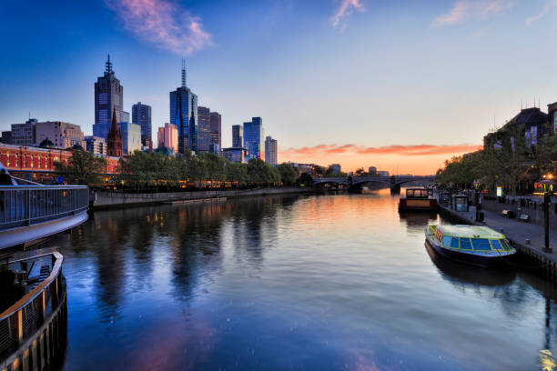 ME CBD Rise from Walkbridge Melbourne city CBD on waterfront along Yarra river with Flinders station and Prince bridge at sunrise reflecting lights in waters of Yarra. south yarra stock pictures, royalty-free photos & images