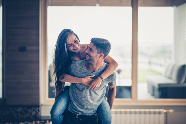 istock Young cheerful couple having fun together while piggybacking at home. 865647308