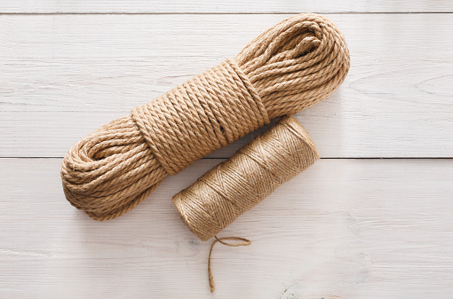 Natural Jute Twine Roll, top view on white wood background. DIY Wrap Gift Hemp Rope Cord String Roll, supplies and tools for handmade hobby leisure