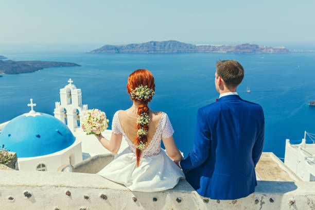 Wedding couple  watching the sea Wedding couple sitting and watching the sea happy couple on vacation in santorini greece stock pictures, royalty-free photos & images