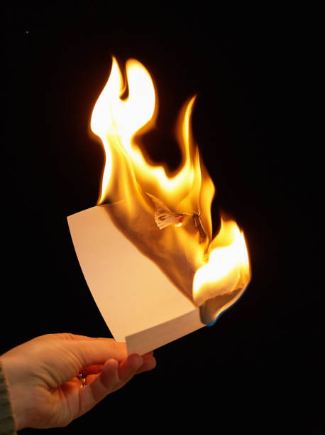 istock Hand holding burning paper against black background 865664072