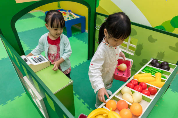 ragazze cinesi asiatiche che giocano di ruolo al negozio di frutta - child playing dressing up imagination foto e immagini stock