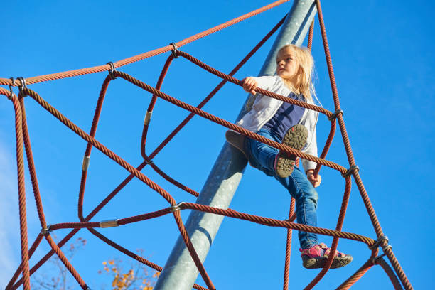 istock Active young child girl climbing the spider web playground activity. 865671528
