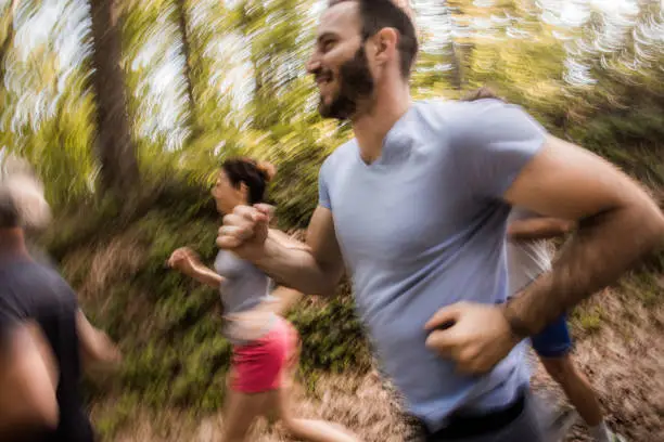 Small group of athletes in blurred motion running a marathon in nature.