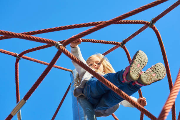 istock Active young child girl climbing the spider web playground activity. 865671802
