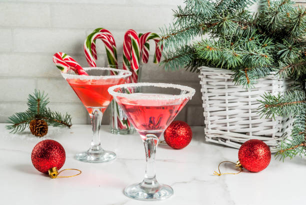 Christmas pink peppermint martini Christmas drinks, pink peppermint martini cocktail with xmas decoration and candy cane sweet on white marble kitchen table, copy space rime ice stock pictures, royalty-free photos & images