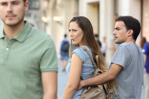 Disloyal woman looking another man and her angry boyfriend Disloyal woman looking another man and her angry boyfriend looking at her on the street edgy man stock pictures, royalty-free photos & images