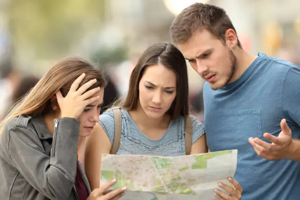 Photo of Three lost tourists trying to find a location in a map