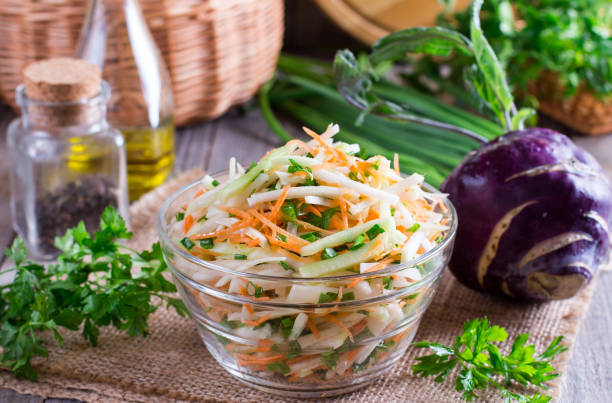 frischer salat mit kohlrabi, gurken, karotten und kräutern in eine schüssel geben. vegetarisches essen. leckeres und gesundes gericht. gesunde ernährung - kohlrabi stock-fotos und bilder