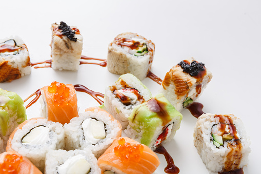 Salmon and philadelphia sushi rolls - asian food restaurant delivery, closeup of platter set on white background, copy space