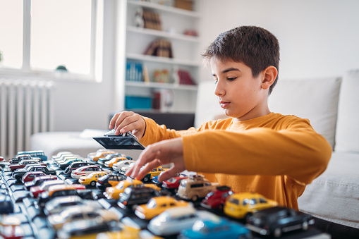 Photo of boy with his small car collection at home