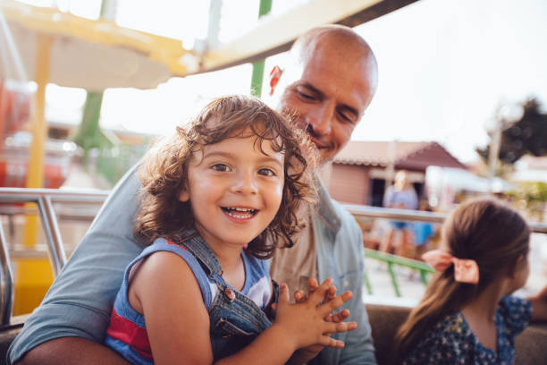 Young children with father on ferris wheel amusement park ride Happy young brother and sister having fun with father on ferris wheel amusement park ride carnival children stock pictures, royalty-free photos & images