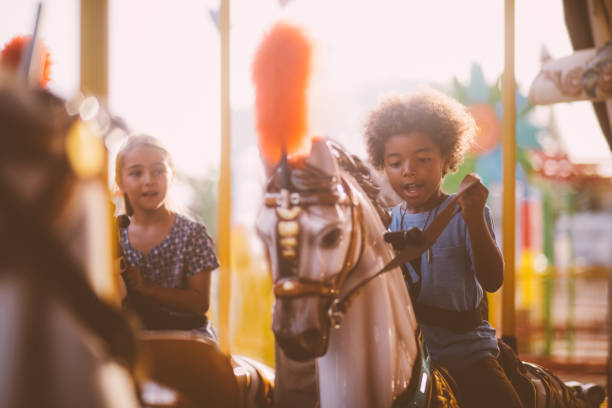 multiethniques enfants s’amusant sur le manège du parc d’attractions ride - carousel merry go round child african descent photos et images de collection