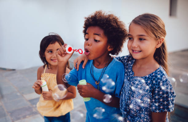 multi-ethnischen kinder beste freunde seifenblasen in den sommerferien - seifenblasenring stock-fotos und bilder