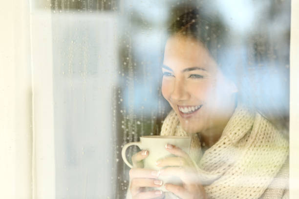istock Happy lady looking through a window in winter 865713208