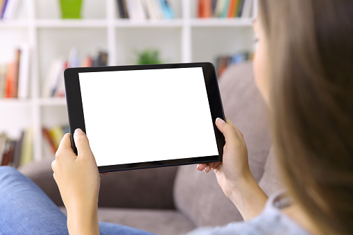 Woman watching media content showing a blank tablet screen sitting on a sofa at home
