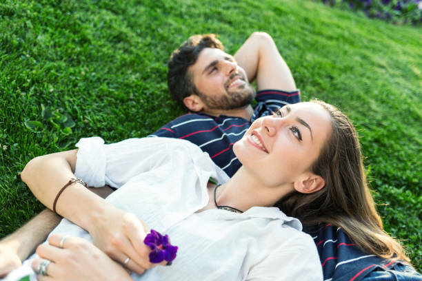 istock Young couple lying on the grass and looking at the sky 865717616