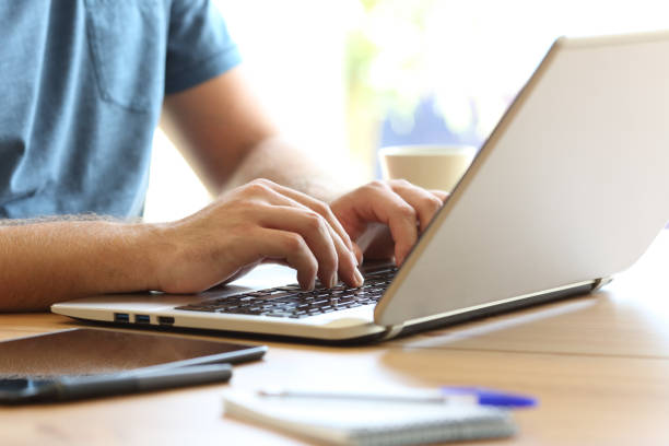 mãos de homem, digitando em um teclado de computador portátil sobre uma mesa - internet success household equipment horizontal - fotografias e filmes do acervo