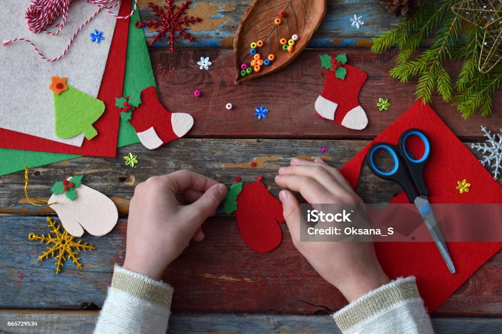 Making of handmade christmas toys from felt with your own hands. Children's DIY concept. Making xmas tree decoration or greeting card. Step 3. Decorate the toy Christmas Stock Photo