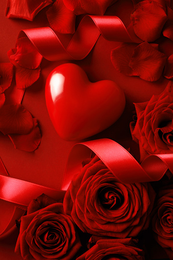Valentine's Day background with red roses and a gift on a dark wood table