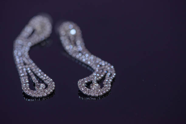 istock Fake diamonds double row prong setting mount hanging earrings with selective focus, positioned on a dark blue glossy surface 865741758